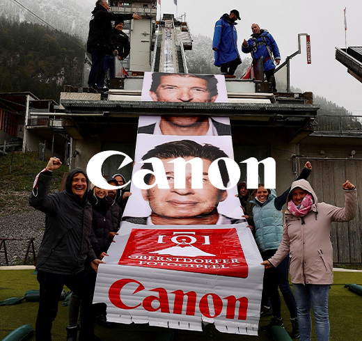 people next to big poster of man next to canon logo