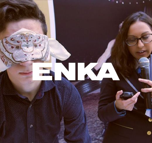 ENKA logo on top of woman holding mic while man is blindfolded 
